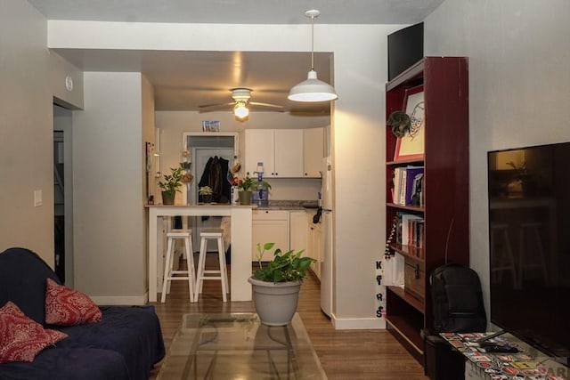 living area with dark wood finished floors, baseboards, and ceiling fan