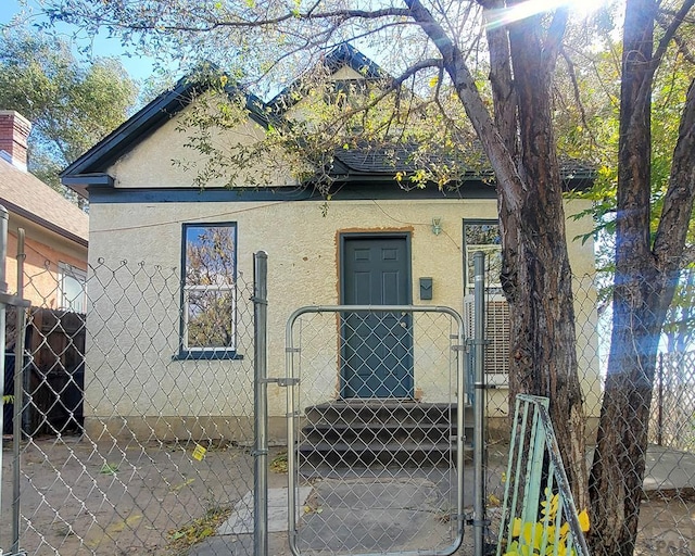 view of front facade featuring a gate, fence, and stucco siding