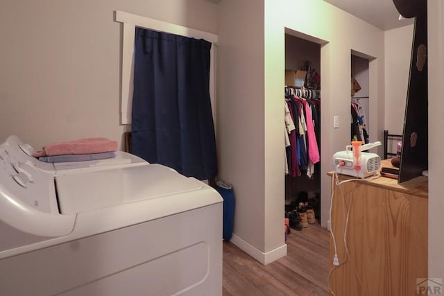 clothes washing area featuring independent washer and dryer, light wood-style flooring, and baseboards