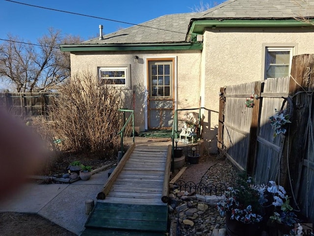 entrance to property with fence and stucco siding