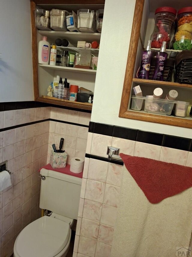 bathroom with tile walls and toilet