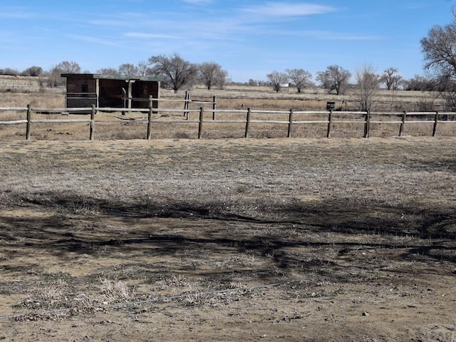 view of yard featuring an outbuilding, an exterior structure, and a rural view