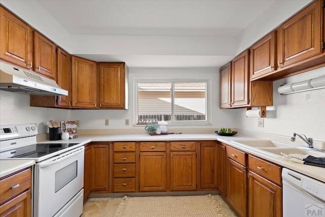 kitchen featuring under cabinet range hood, white appliances, a sink, light countertops, and brown cabinets