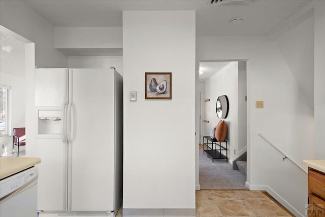 kitchen featuring white appliances, baseboards, and light countertops