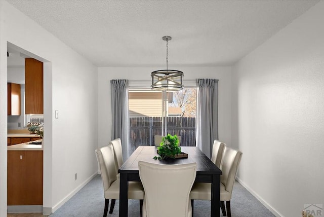 dining room featuring a textured ceiling, carpet flooring, and baseboards