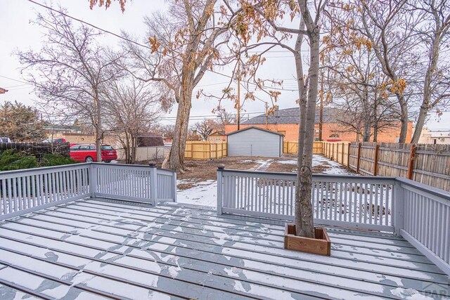 wooden deck with a fenced backyard, a storage unit, and an outbuilding