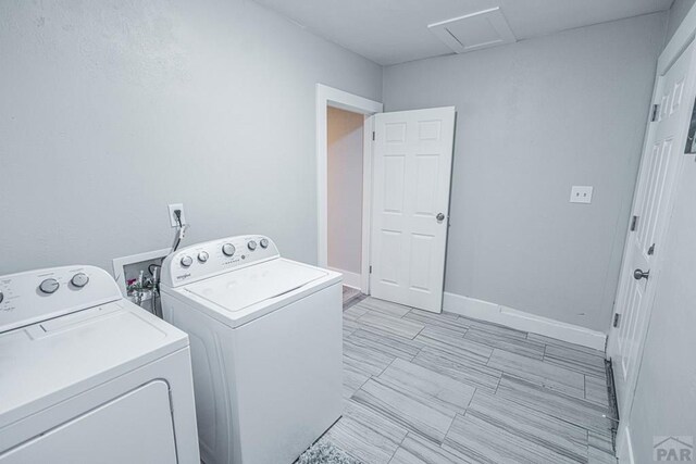 clothes washing area with laundry area, separate washer and dryer, attic access, and baseboards