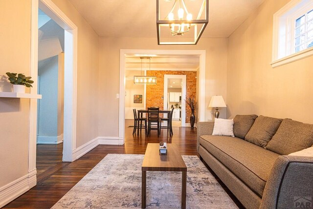 living area featuring dark wood-type flooring, baseboards, and an inviting chandelier