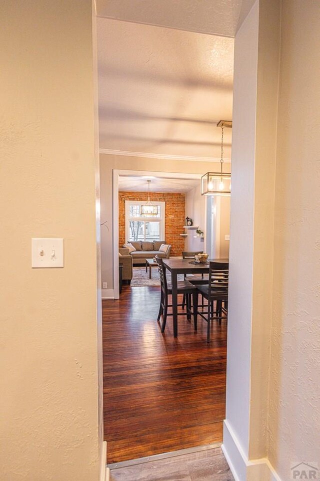 dining area with crown molding, a textured wall, wood finished floors, and baseboards