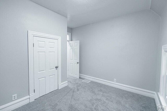 carpeted spare room with visible vents and baseboards