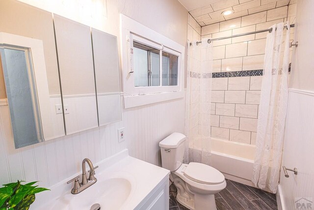 full bathroom featuring toilet, a wainscoted wall, wood finished floors, vanity, and shower / tub combo with curtain