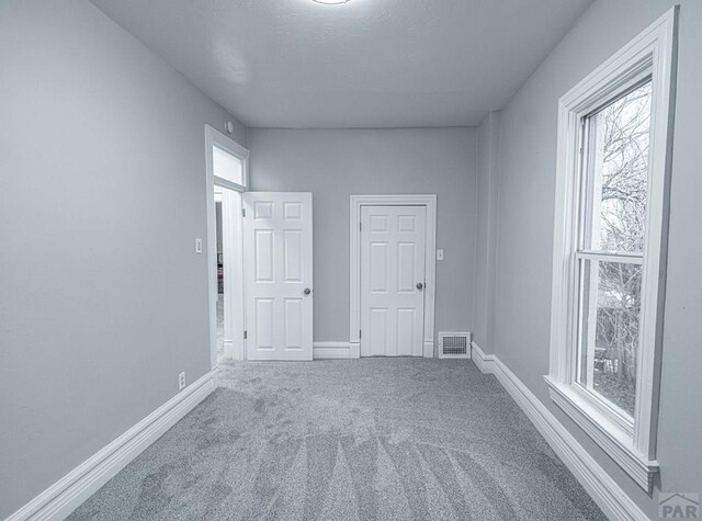 carpeted empty room with visible vents and baseboards