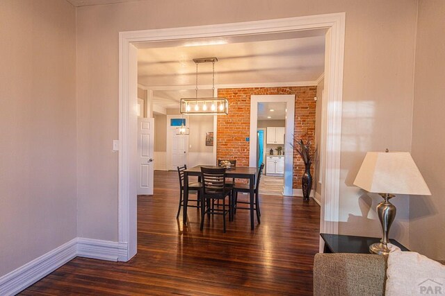 dining space with brick wall, dark wood-type flooring, and baseboards