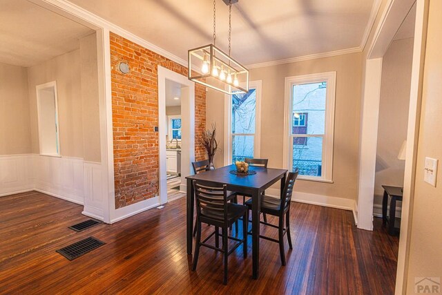 dining area with dark wood-style floors, brick wall, visible vents, and crown molding