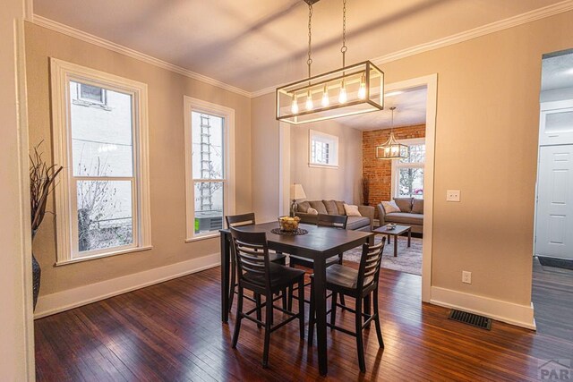 dining space featuring dark wood-style floors, visible vents, crown molding, and baseboards