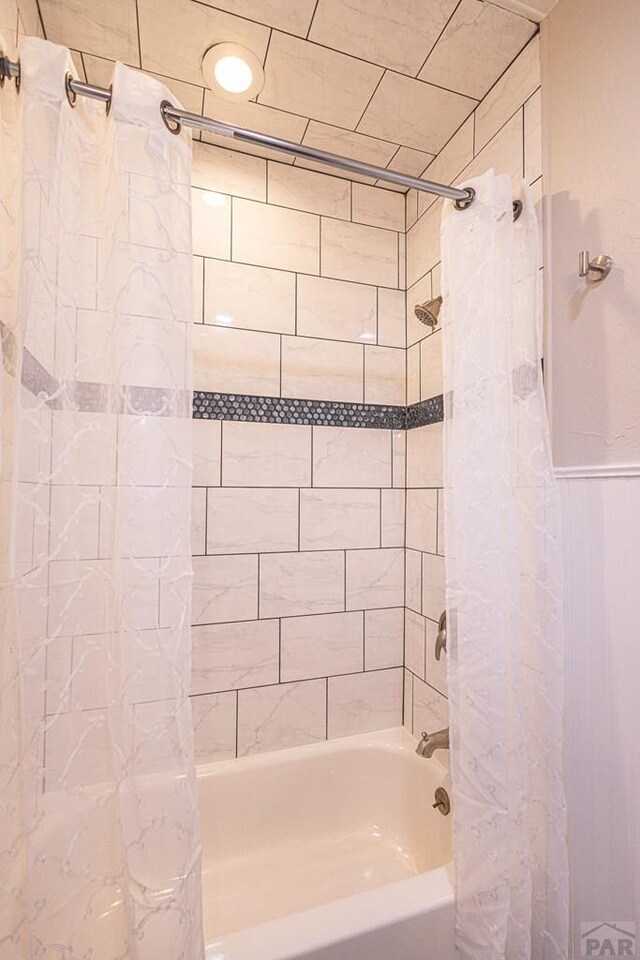 full bath with a wainscoted wall and shower / bath combo with shower curtain