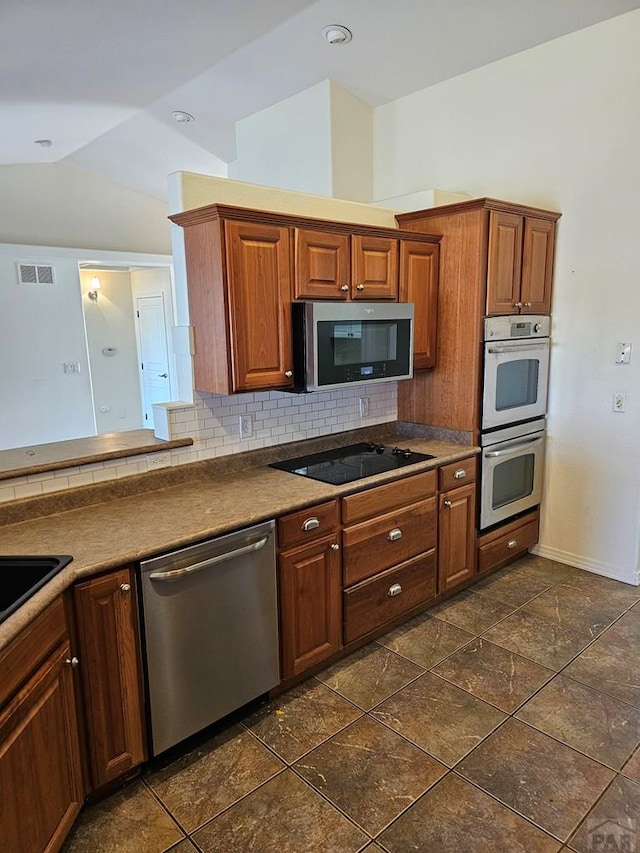 kitchen featuring tasteful backsplash, visible vents, appliances with stainless steel finishes, lofted ceiling, and baseboards