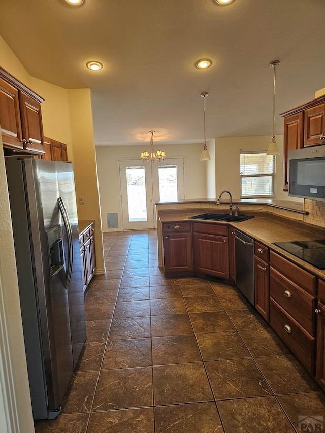kitchen featuring a sink, decorative light fixtures, a notable chandelier, and stainless steel appliances