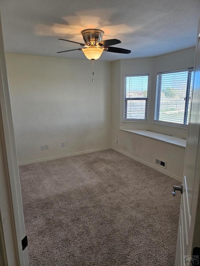 unfurnished room with carpet flooring, baseboards, a ceiling fan, and visible vents