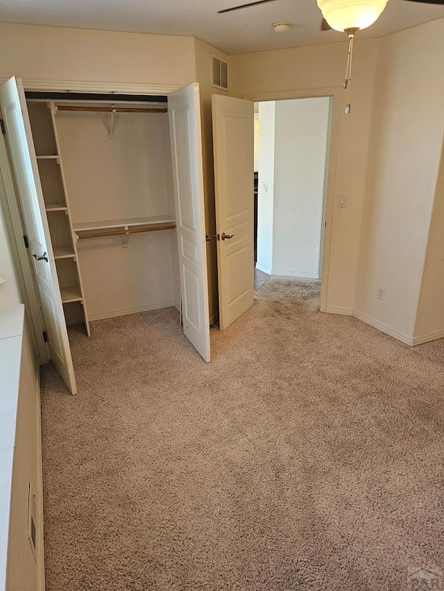 unfurnished bedroom with light carpet, visible vents, a closet, and baseboards