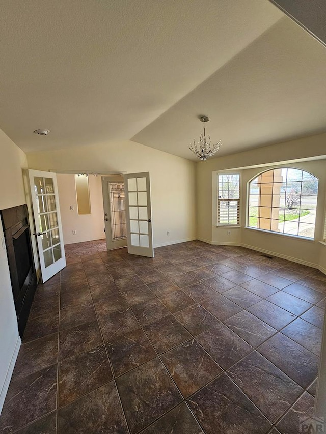 empty room with french doors, an inviting chandelier, baseboards, and lofted ceiling