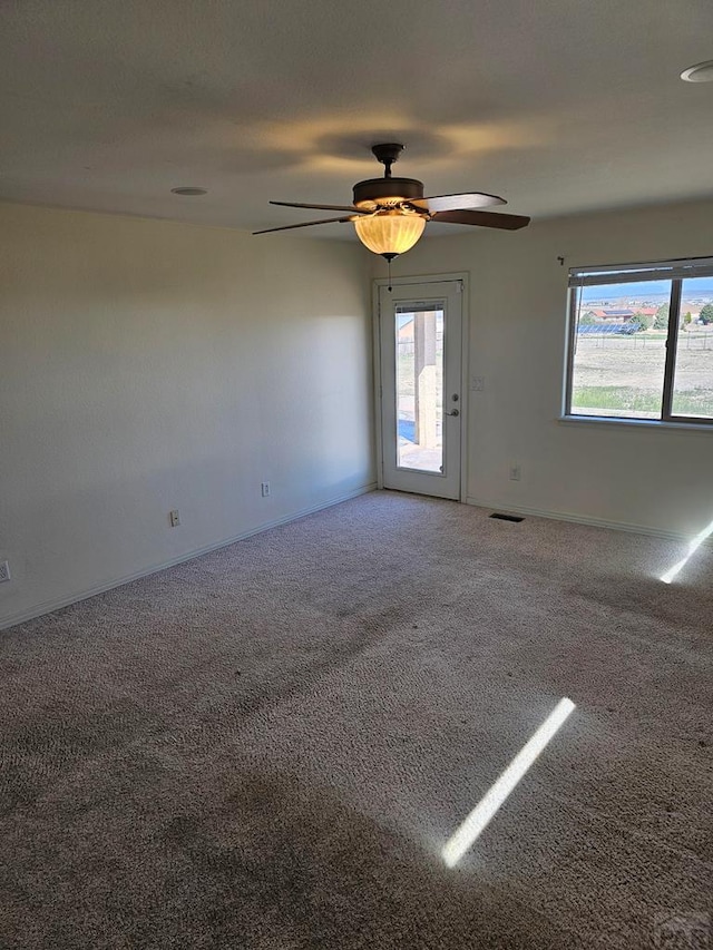 carpeted empty room featuring visible vents, baseboards, and a ceiling fan