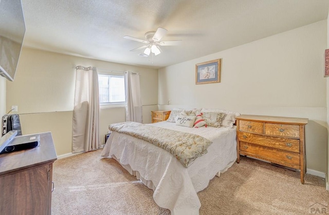 bedroom featuring baseboards, light colored carpet, a ceiling fan, and a textured ceiling