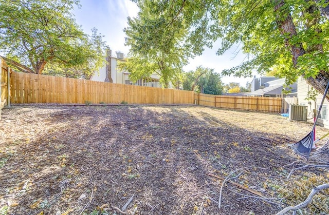 view of yard with central AC unit and a fenced backyard