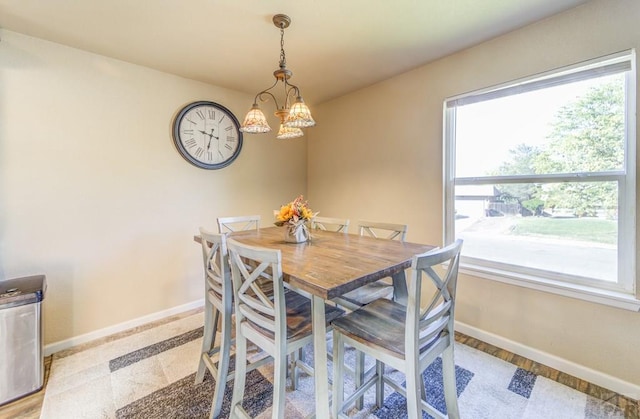 dining space featuring a chandelier and baseboards