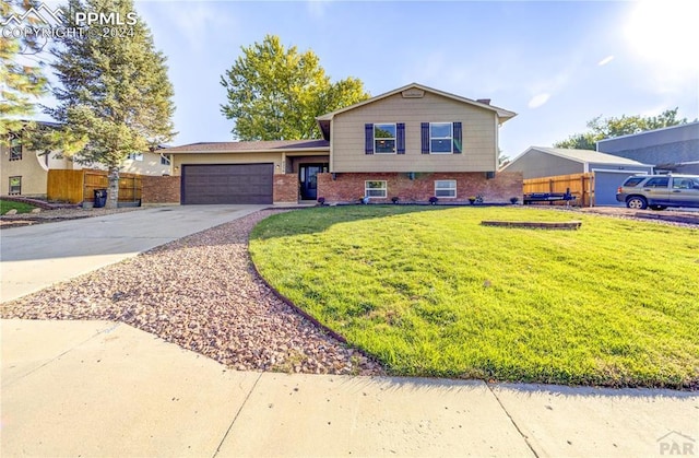 tri-level home featuring a front yard, fence, concrete driveway, a garage, and brick siding