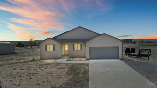 ranch-style house featuring a garage, driveway, and stucco siding