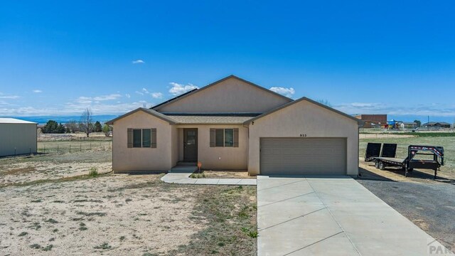 ranch-style home featuring an attached garage, fence, concrete driveway, and stucco siding