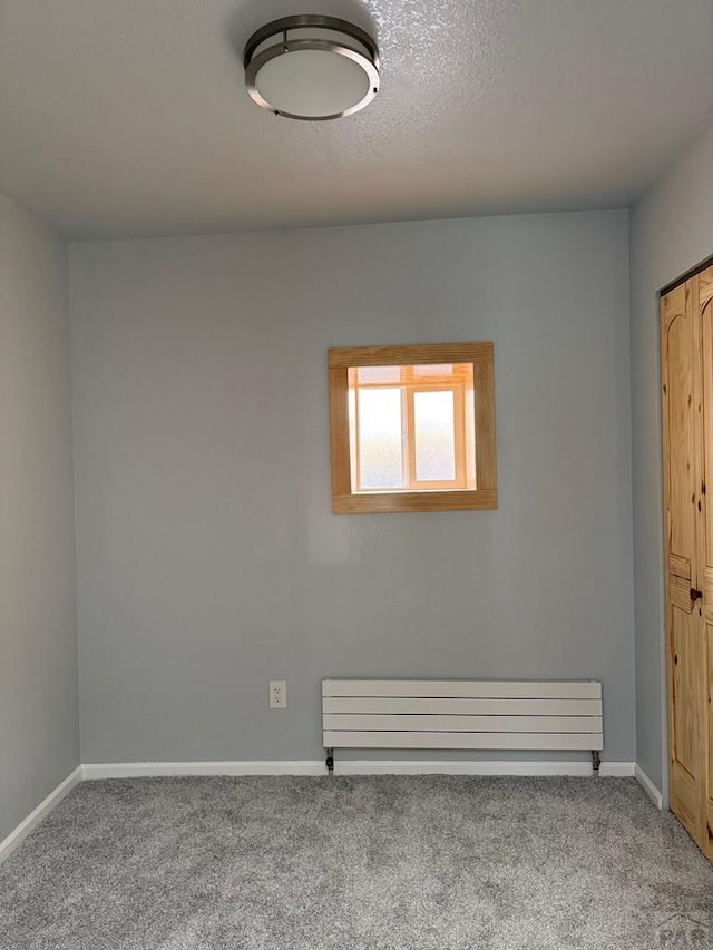 carpeted spare room with a textured ceiling and baseboards