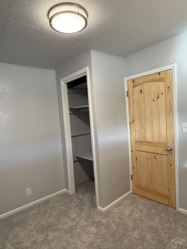 unfurnished bedroom featuring carpet floors, a textured ceiling, baseboards, and a closet