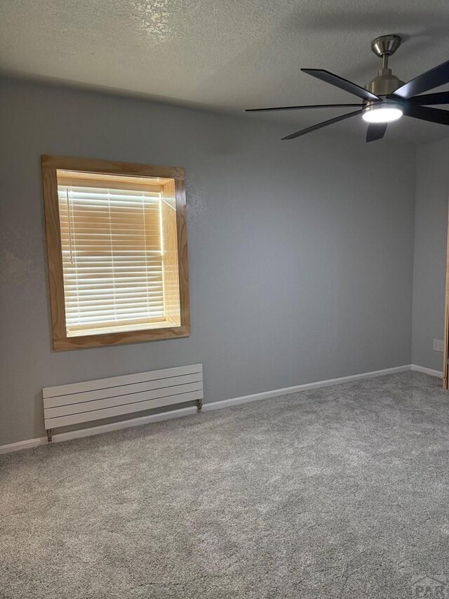 unfurnished room featuring a textured ceiling, radiator heating unit, and baseboards