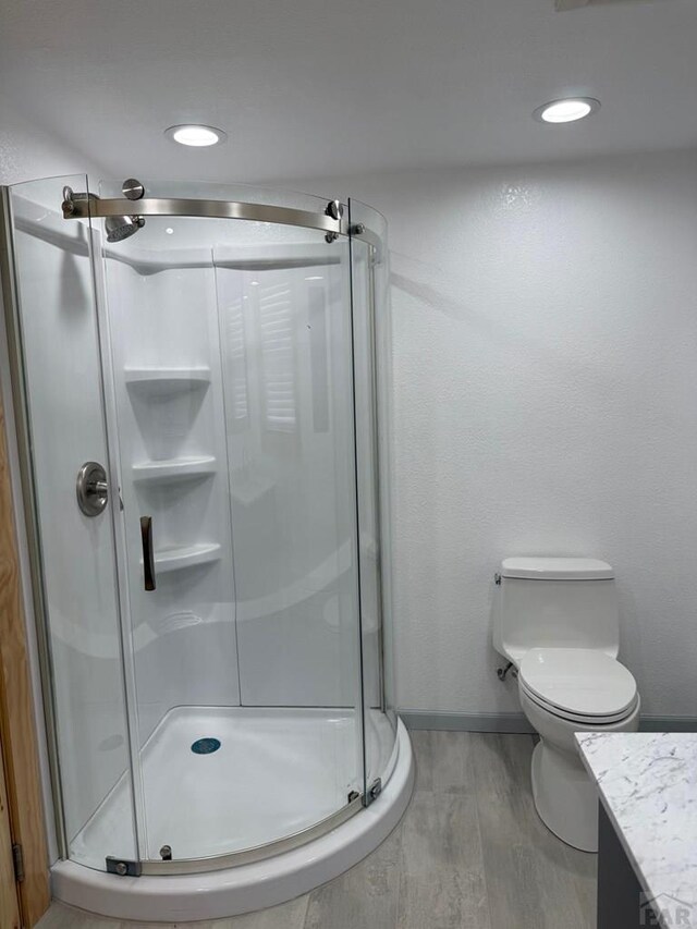 full bath with baseboards, toilet, wood finished floors, vanity, and a shower stall