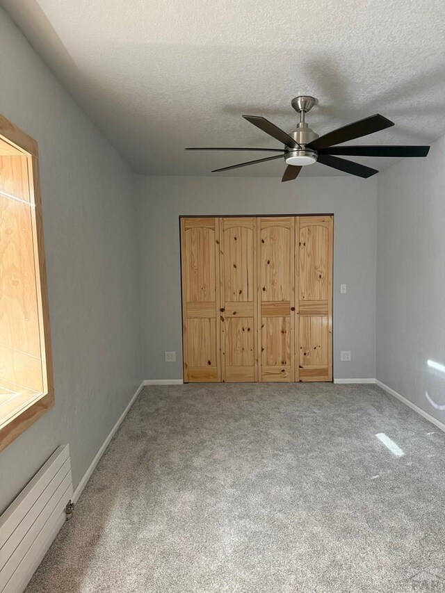 unfurnished bedroom with a textured ceiling, carpet, and baseboards