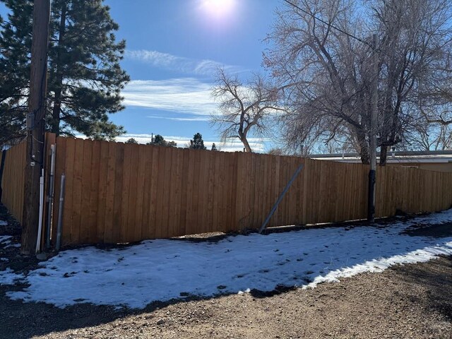 yard covered in snow featuring fence