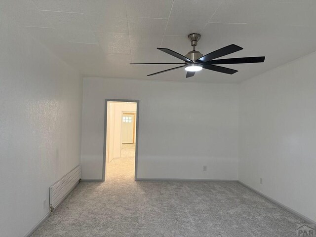 unfurnished room featuring a ceiling fan, light carpet, and baseboards