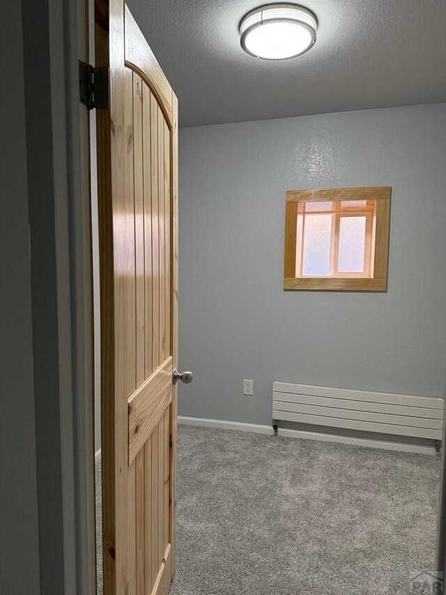 unfurnished room with carpet floors, baseboards, a textured ceiling, and a textured wall