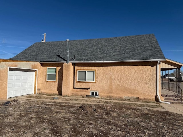 exterior space with an attached garage, stucco siding, and roof with shingles