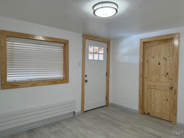 entryway with baseboards, light wood finished floors, and radiator