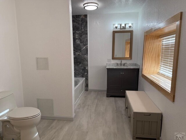 bathroom with toilet, vanity, a textured ceiling, wood finished floors, and baseboards