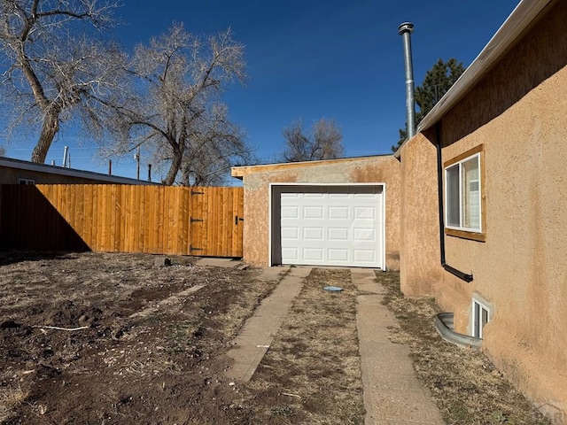 exterior space with fence, an attached garage, and stucco siding