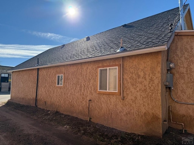 view of home's exterior with a shingled roof and stucco siding