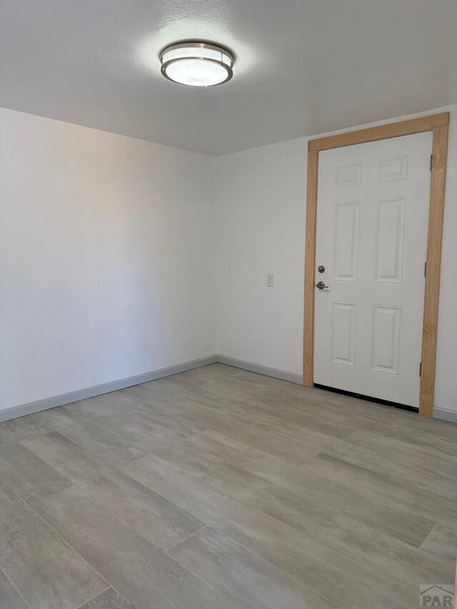 spare room featuring a textured ceiling and baseboards