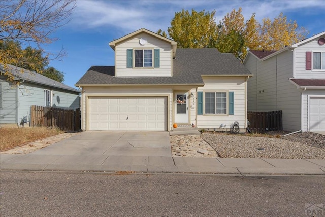 traditional home with an attached garage, driveway, fence, and roof with shingles