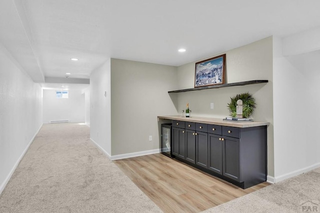 hallway with light wood-style floors, recessed lighting, light colored carpet, and baseboards