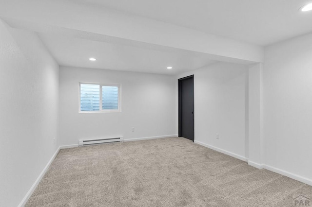 spare room featuring a baseboard heating unit, recessed lighting, light colored carpet, and baseboards