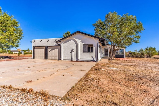 view of front of property with a garage, driveway, and stucco siding